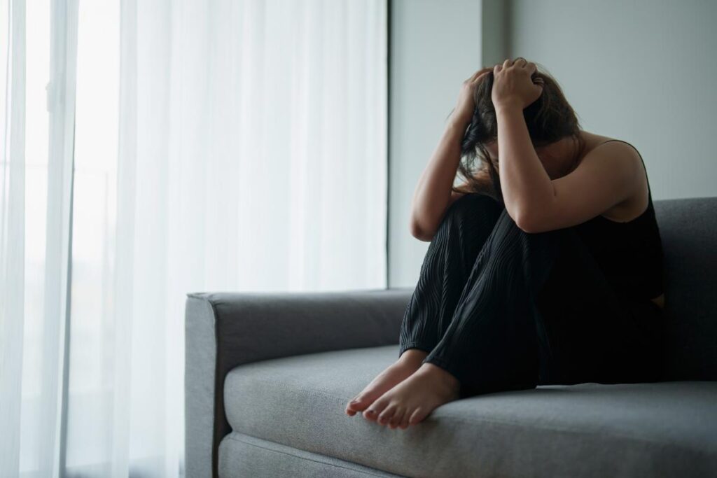 a person dealing with addiction relapse triggers sits on a couch in distress