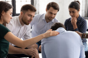 people look and console man who is slumped over while they learn more about 12 step programs for families