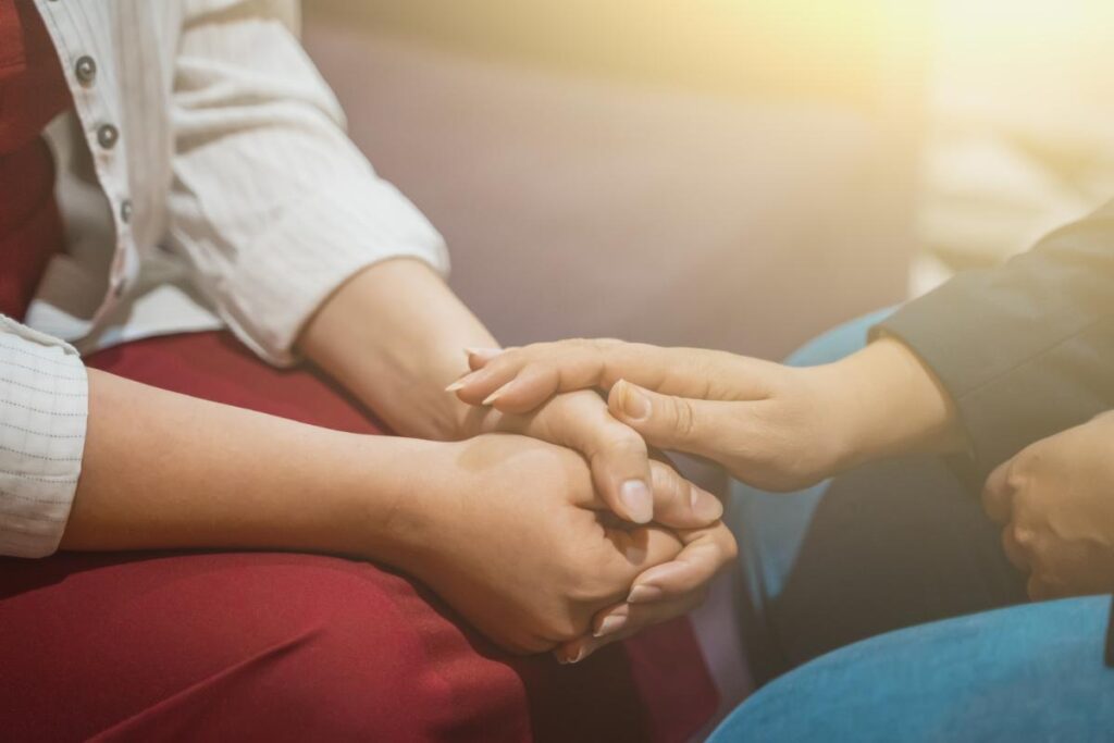 a preson holds their hands in their lap and asks how to overcome the fear of opioid withdrawal while a friend touches their hand trying to comfort them