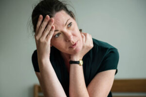 a woman sits with her hands to her head and neck thinking about the psychological effects of heroin abuse