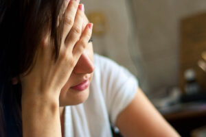 a woman distraught by the causes and effects of meth abuse holds her hand to her head