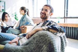 a man sits on a chair smiling after learning about evoke waltham