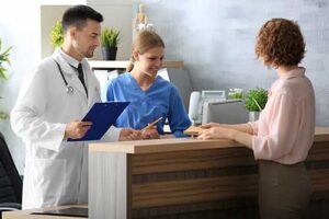 a doctor and a nurse help a woman patient find a day treatment program for addiction and hand the patient some paperwork