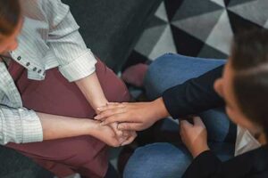 a person touches another person's folded hands while in a dialectical behavior therapy program