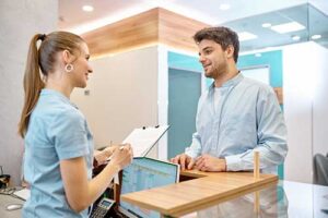 a male patient talks to a female receptionist at a treatment center while enrolling in a drug addiction treatment program