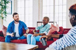 three people sit on couches and talking to each other while in a reality therapy program