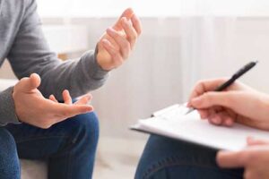 a photo of a man's hands and a therapist hand's writing down notes during the man's solution focused therapy program