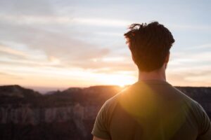 a man stares at sunset while thinking about how mindfulness can help you and loved ones