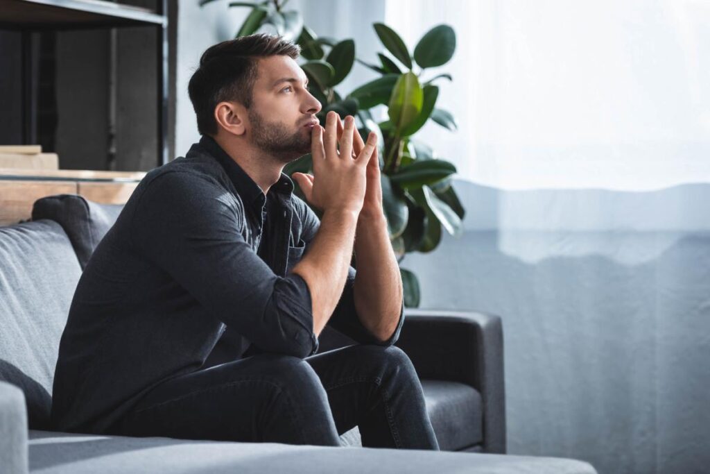 a man sits on a couch and thinking hard about the long-term effects of anxiety