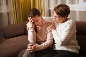 an older woman consoles a younger woman with a hug after learning how helping an addicted family member can be crucial to their recovery