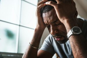 a man has his hands to his temples looking uncomfortable and upset about opioid abuse in massachusetts