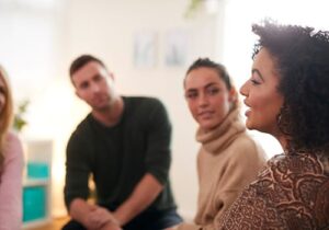 a woman talks in her group therapy session while participating in her opioid addiction treatment program