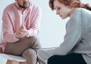 a distraught woman looks away from her therapist while in relapse prevention therapy