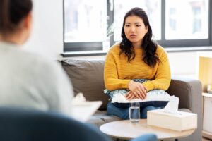 a patient sits on a couch while talking with her therapist about cbt, dbt, and addiction