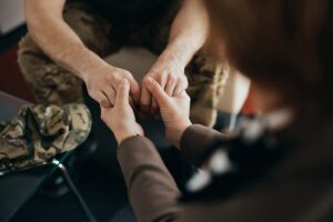 a photo of two people holding each other hands while discussing the connection between veterans and substance abuse