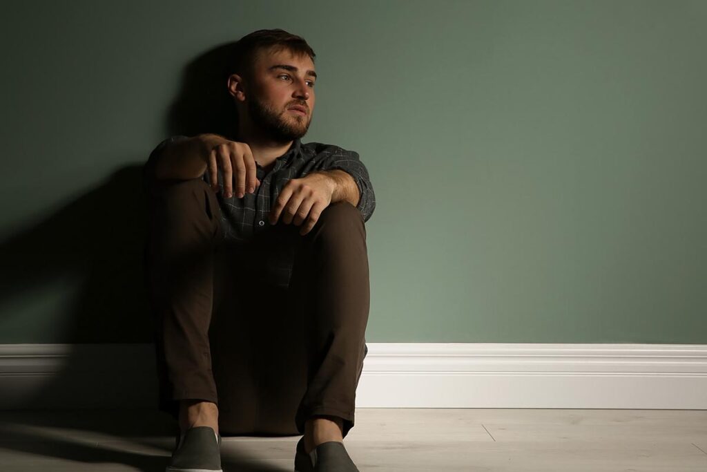 a man sits on the floor of his apartment thinking about drug tolerance dependence and addiction