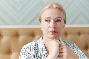 woman sits while holding her hands near her face and looking off in the distance thinking about the link between ptsd and alcohol abuse