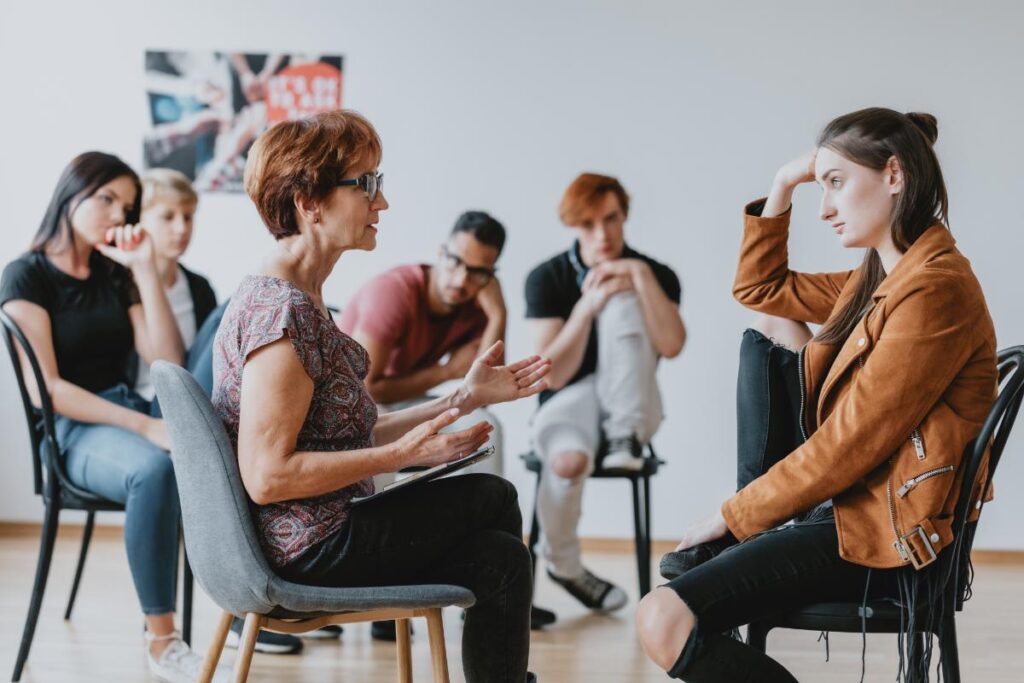 people in a group session sit around and talk to each other and sharing outpatient rehab resources in massachusetts