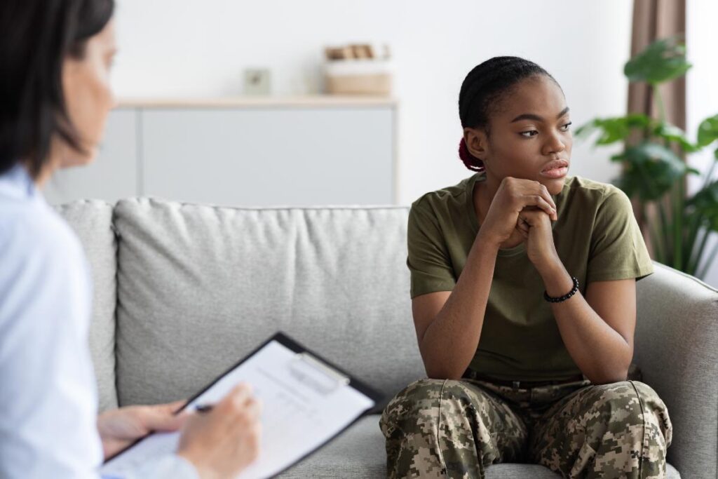 a military person sits on a couch listening to a therapist discuss the connection between ptsd substance abuse and veterans