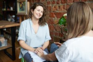 a woman smiles while looking at a person consoling her in her person-centered therapy program