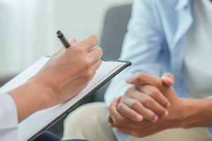 a therapist takes notes while a patient has hands clasped together in their schizoaffective disorder treatment program