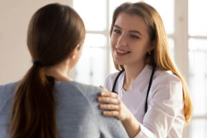 a rehab specialist touches the shoulder of a woman patient and explains to her about how to get help after an overdose