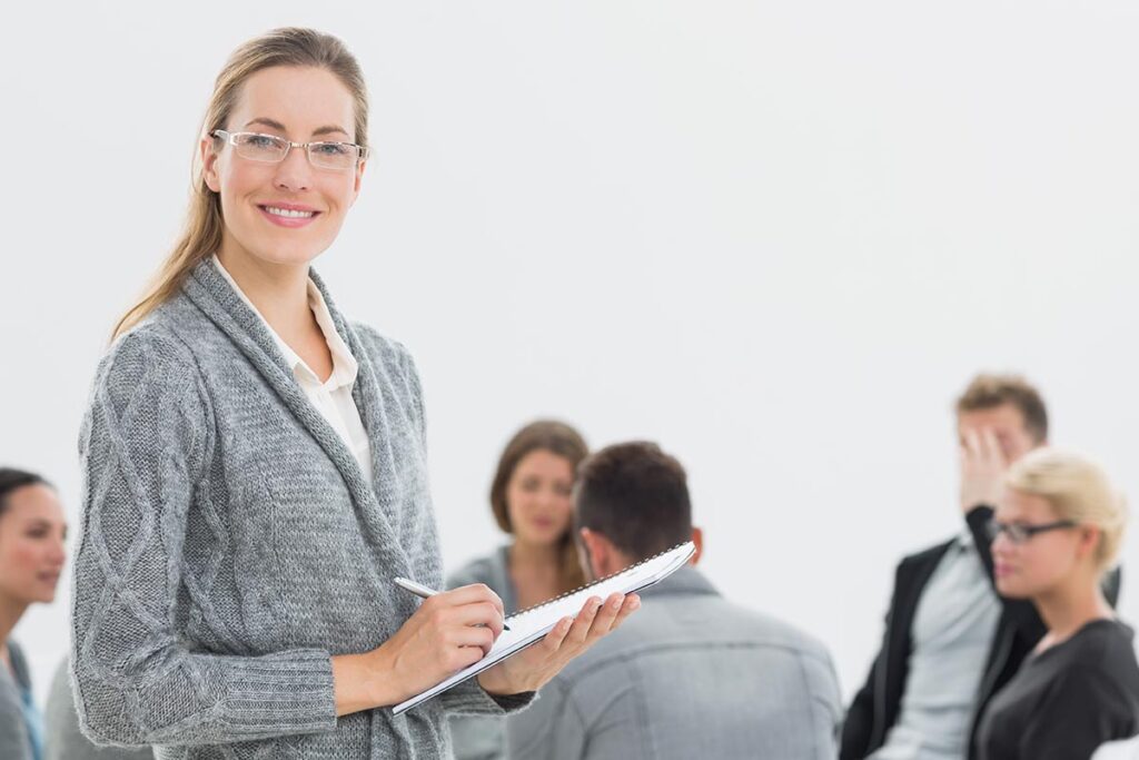 a woman with a clipboard takes notes while talking to a group of people at vivitrol treatment in massachusettss