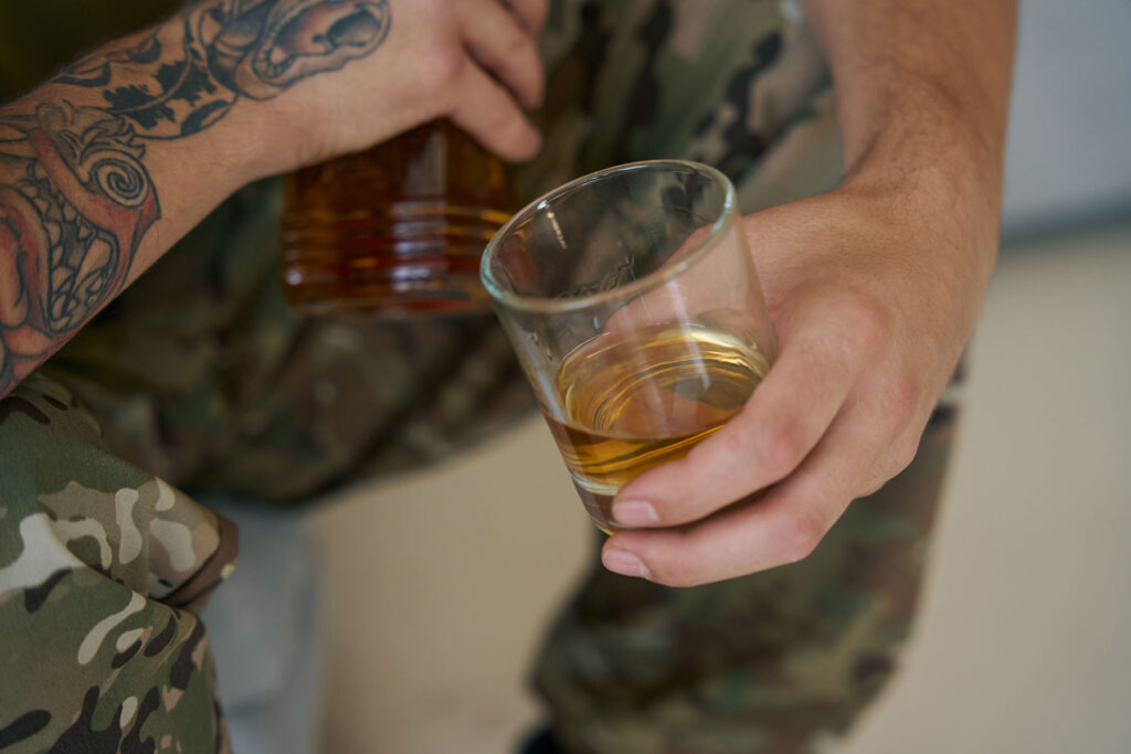 a person in a military uniform holds an alcoholic beverage and is dealing with substance abuse in the military