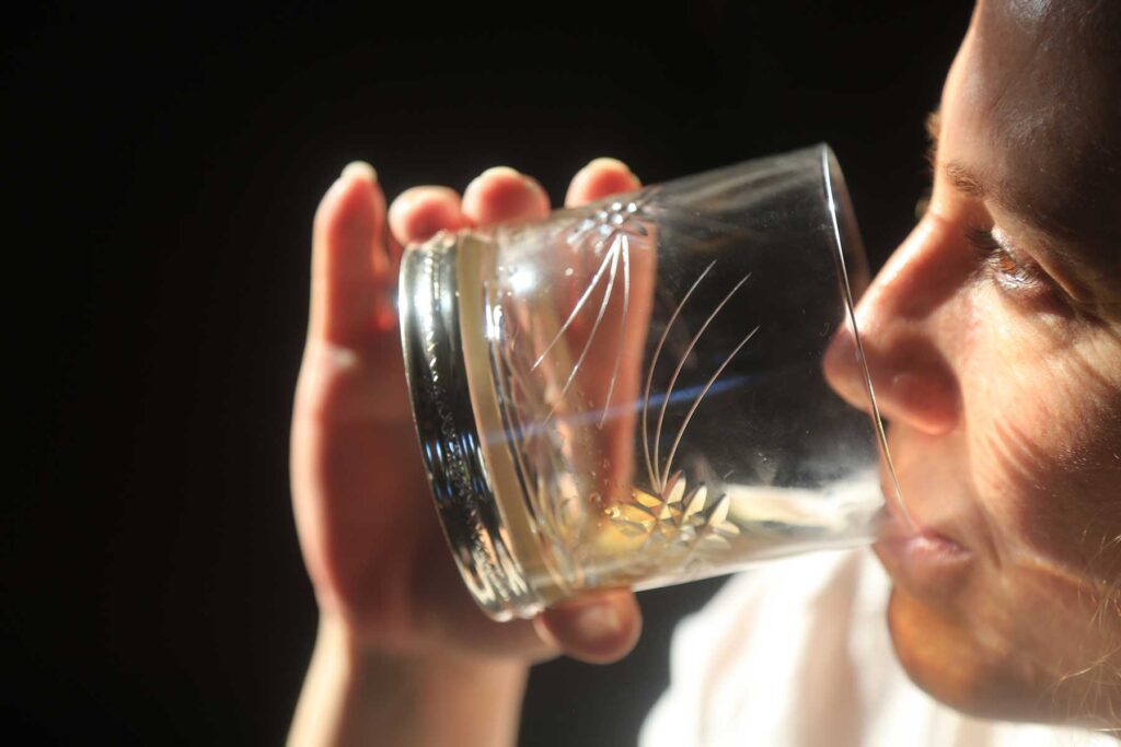 a man holds a glass of whiskey to his face and drinks it while wondering what to do when drinking becomes a problem