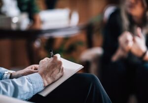 a person is taking notes on a notepad while attending their ecstasy rehab program