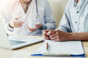 a doctor sits with a patient searching for a suboxone doctor in Massachusetts on the doctor's laptop as the patient takes notes