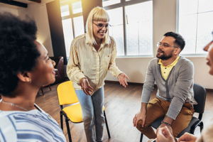 a blonde woman gets up from her chair where she was sitting with other group members in her outpatient program