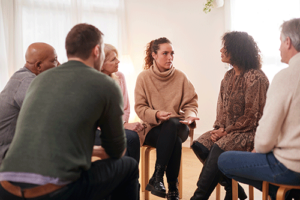 a woman sits with five other group members in a circle in the womans painkiller rehab program