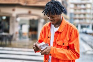 a young male adult is outside and looking through his wallet while thinking about how much does outpatient rehab cost