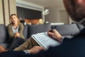 a therapist takes notes with a patient during a talk about the benefits of women's addiction treatment