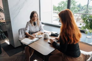 a woman patient sits at a table with a counselor who is taking notes in the patients holistic counseling session