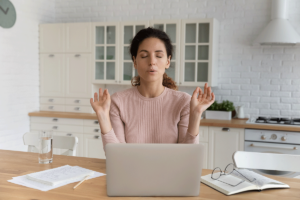 woman sits at a table with her laptop learning about ways of managing her anger