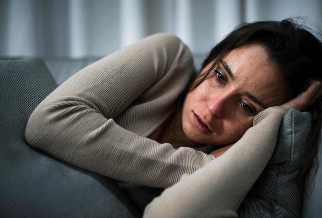 a woman lays on a couch and is struggling with meth withdrawals symptoms