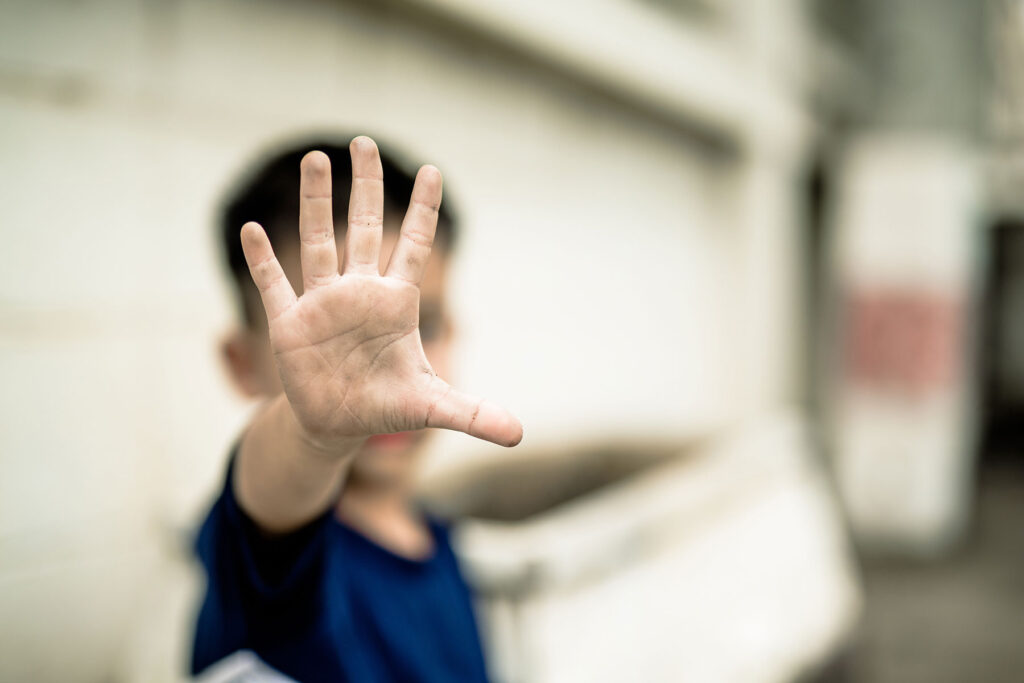 small child holds his hand up in front of his face while working through his childhood trauma and relationships issues with parents