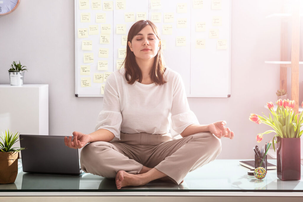 woman sits crossed legged on the ground meditating trying to ease her stress and anger