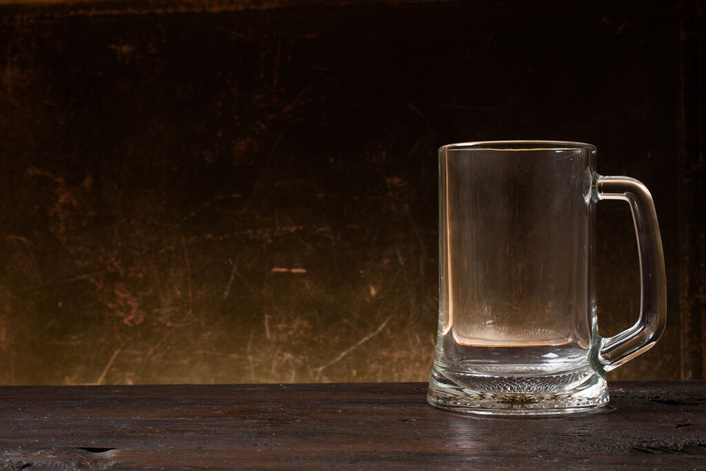 an empty beer mug sits on a table while the person drinking wonders if they have an alcohol dependence